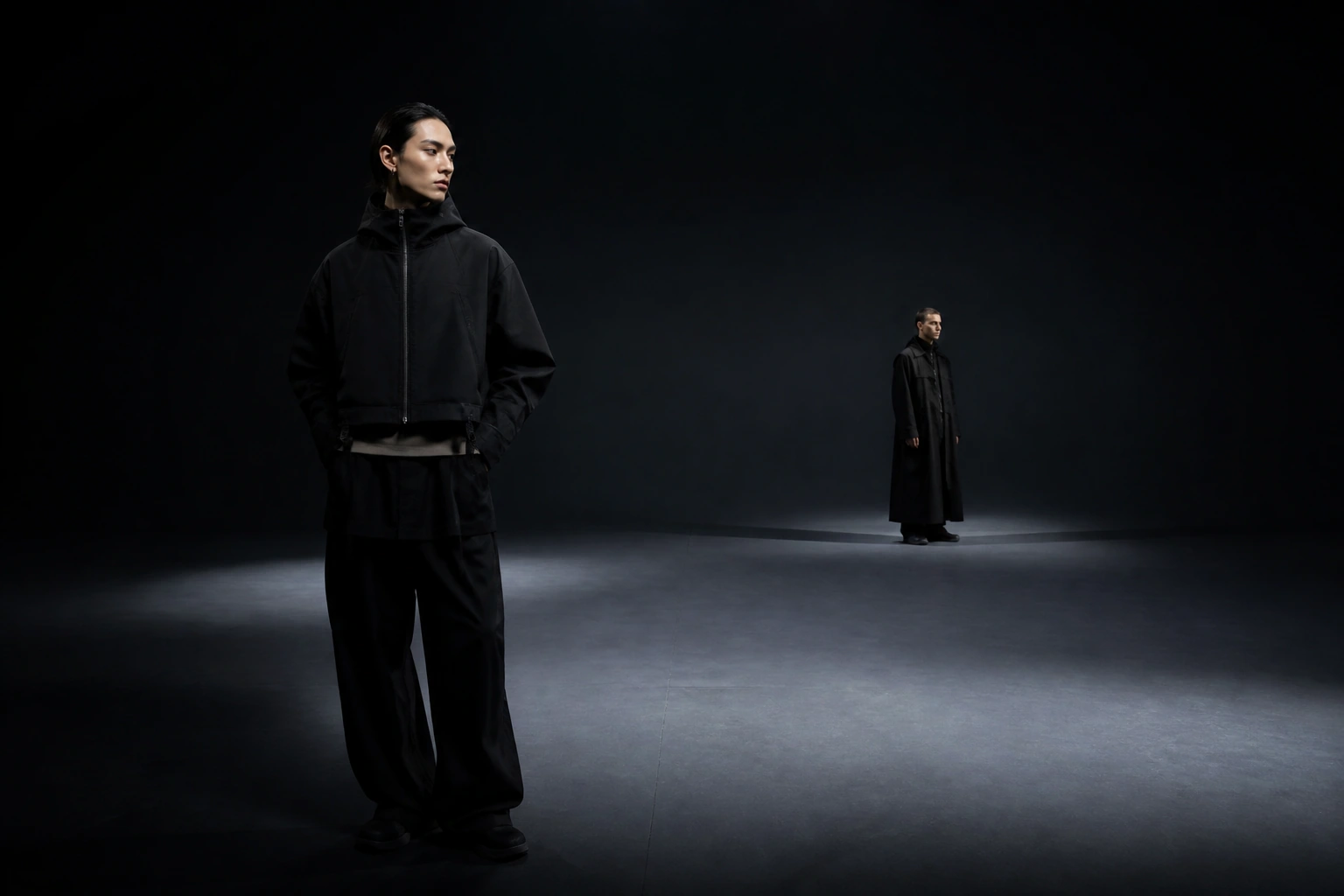 Two models in black outerwear inside a nocturnal studio